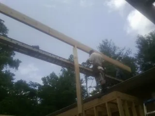 Carpenter setting a ridge beam over a new addition frame — Ice Dam Removal by Roofing Brothers in Brookings