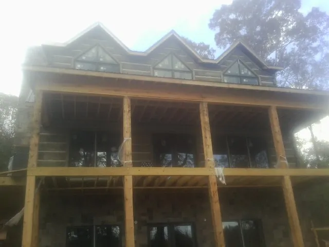 Dormers and porch framing on a large log home under construction — Roof Coating work by our crew in Brookings