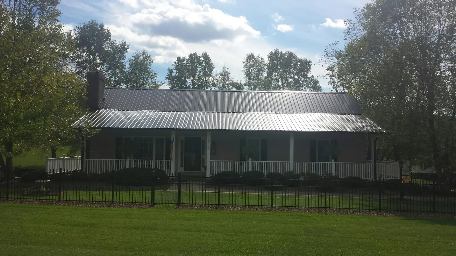 Gray metal roof on a brick ranch with a full width front porch — Gutter Guard Installation work by our crew in Brookings