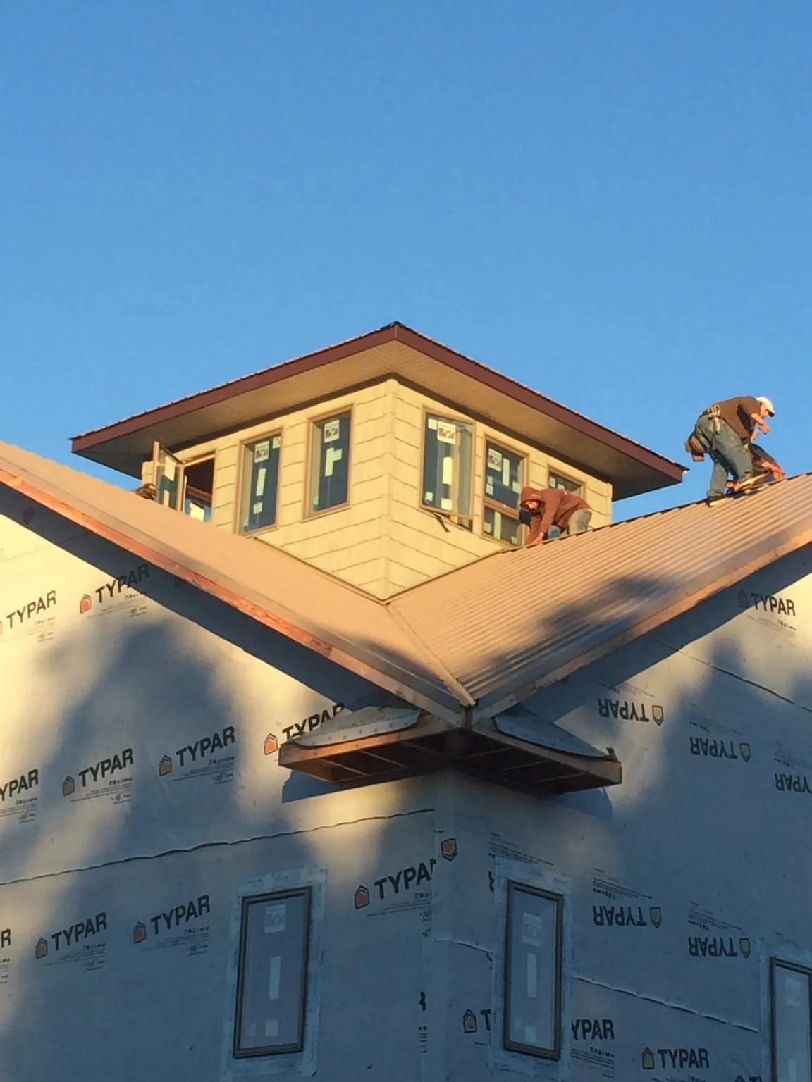 Roofers working around a rooftop cupola on a new metal roof at sunset — Roof Waterproofing in Brookings by Roofing Brothers